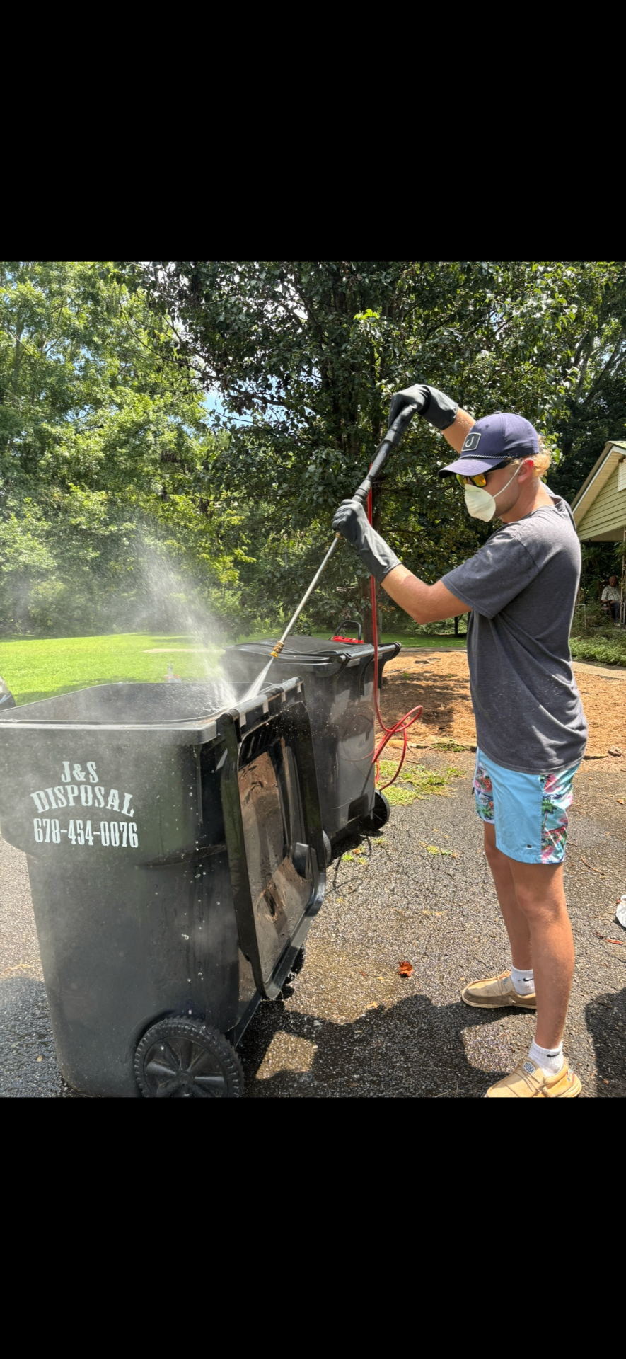 Cody pressure-washing a curbside trash can with hot water